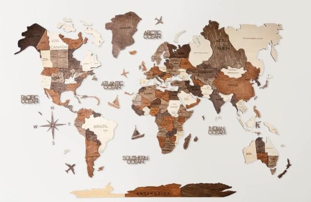 A decorative wooden world map with country outlines hanging on a wall, featuring a variety of wood tones and textures.