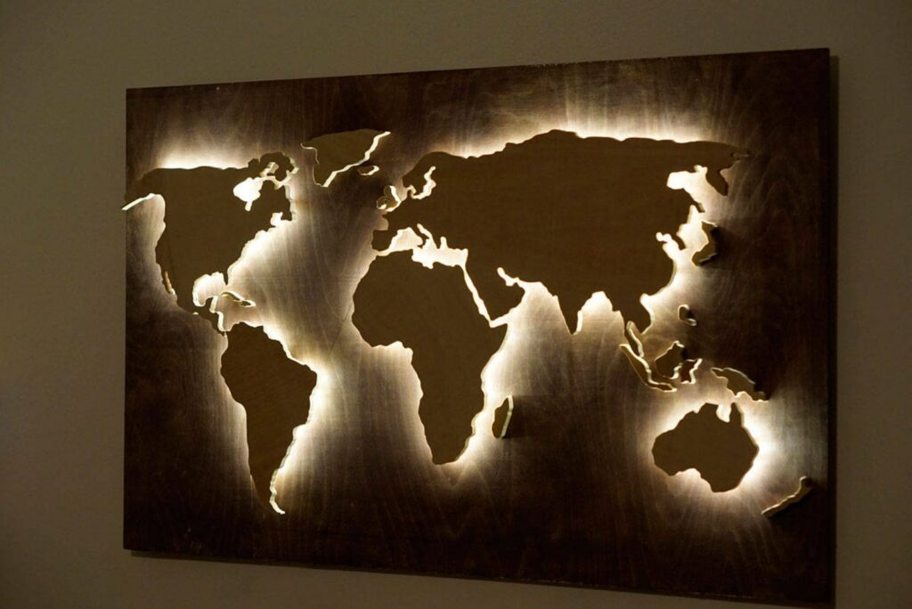 A wooden world map with backlighting mounted on a wall.