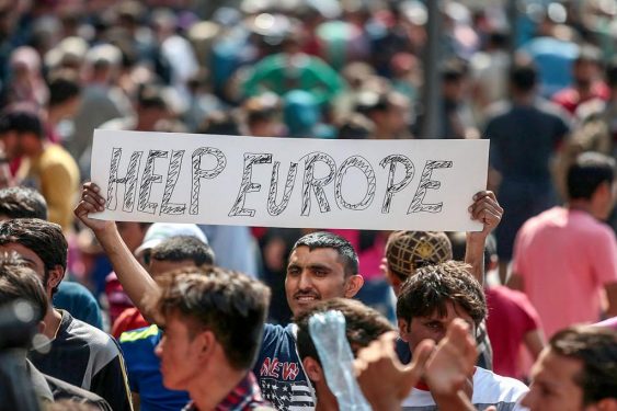 A crowd of people with one individual holding a sign that reads "HELP EUROPE."