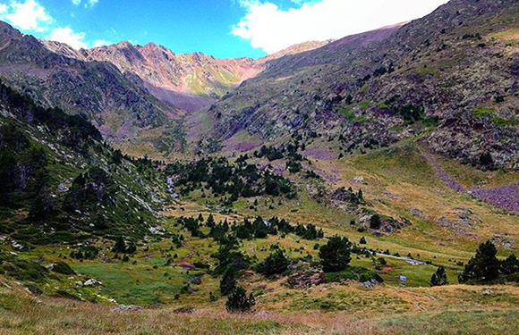 A scenic view of a mountainous landscape with greenery and a clear sky.