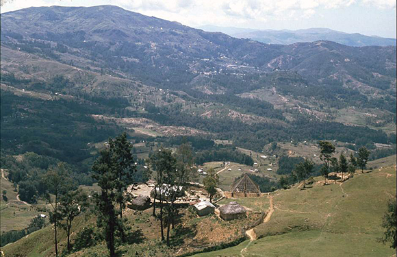 A scenic view of a mountainous landscape with a small rural village nestled among green hills.