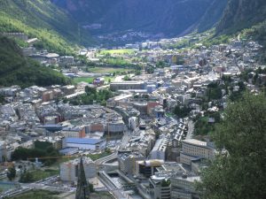 Aerial view of a densely built town nestled in a valley with surrounding mountains, featuring a mix of residential and commercial buildings.