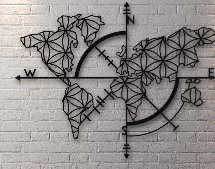 A metal wall art piece featuring the world map with a compass design, mounted on a white brick wall.