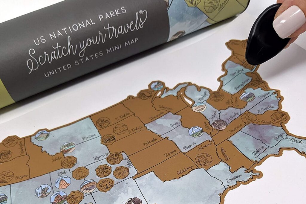 A scratch-off map of US National Parks with some areas scratched off, revealing colors and details underneath, and a coin positioned next to the map.