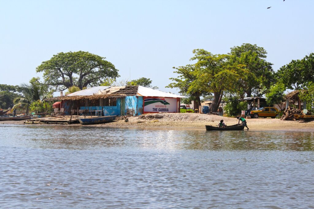 A view of the river and a building with the words, "Welcome to The Gambia" painted on the wall.