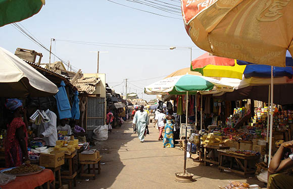 People walking through stalls in the Brikama Market.