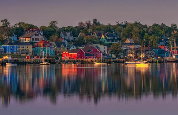 A picturesque waterfront with colorful buildings reflected in calm water during twilight.