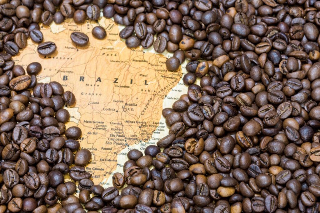 A map of Brazil partially covered with roasted coffee beans.