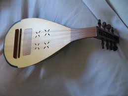 A traditional stringed musical instrument with a pear-shaped body, a long neck, and a flat top with sound holes, lying on a fabric surface.