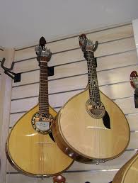 Two bouzoukis hanging on a white wall display.