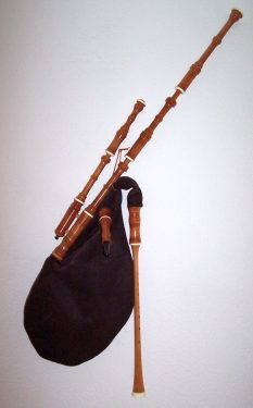 A set of traditional bagpipes with a black bag and wooden pipes against a white background.