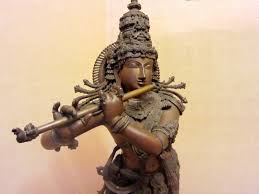 A statue of Lord Krishna playing the flute, with detailed carvings and traditional attire.