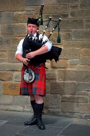 A man in traditional Scottish attire playing the bagpipes.