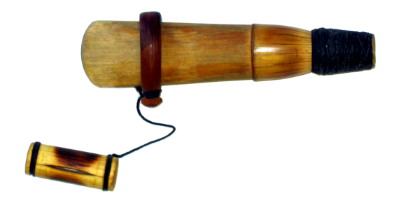 A wooden duck call with a barrel, insert, and a reed attached by a short metal band and a looped cord.