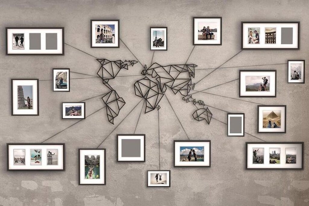 A metal world map wall art piece with photo frames arranged around it on a textured wall.