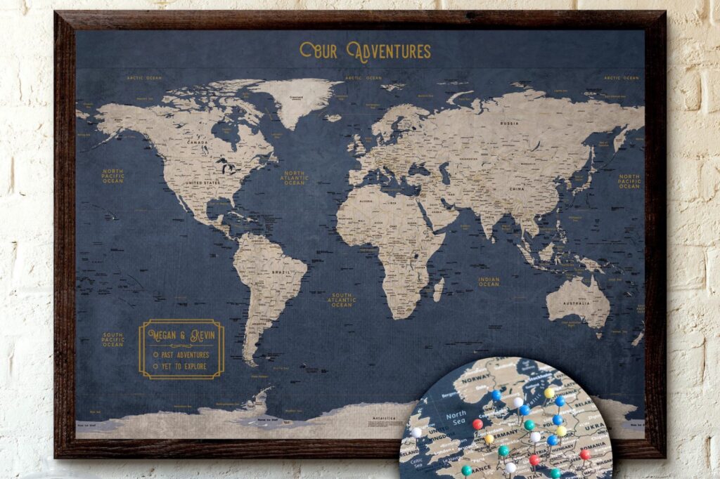 A framed world map wall art with push pins marking various locations, accompanied by a plate of additional pins, against a white brick wall.