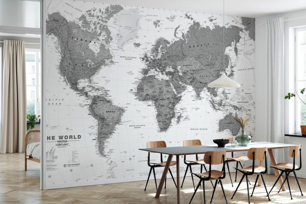 A grayscale world map wallpaper adorns a wall in a modern dining room with a wooden table and chairs.