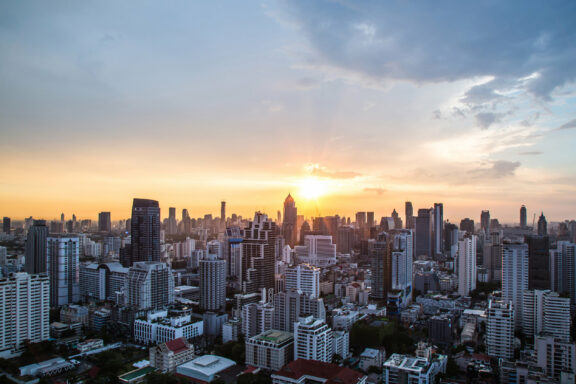 Sunset over the skyline of Johannesburg, South Africa, with silhouetted buildings against a cloudy sky.