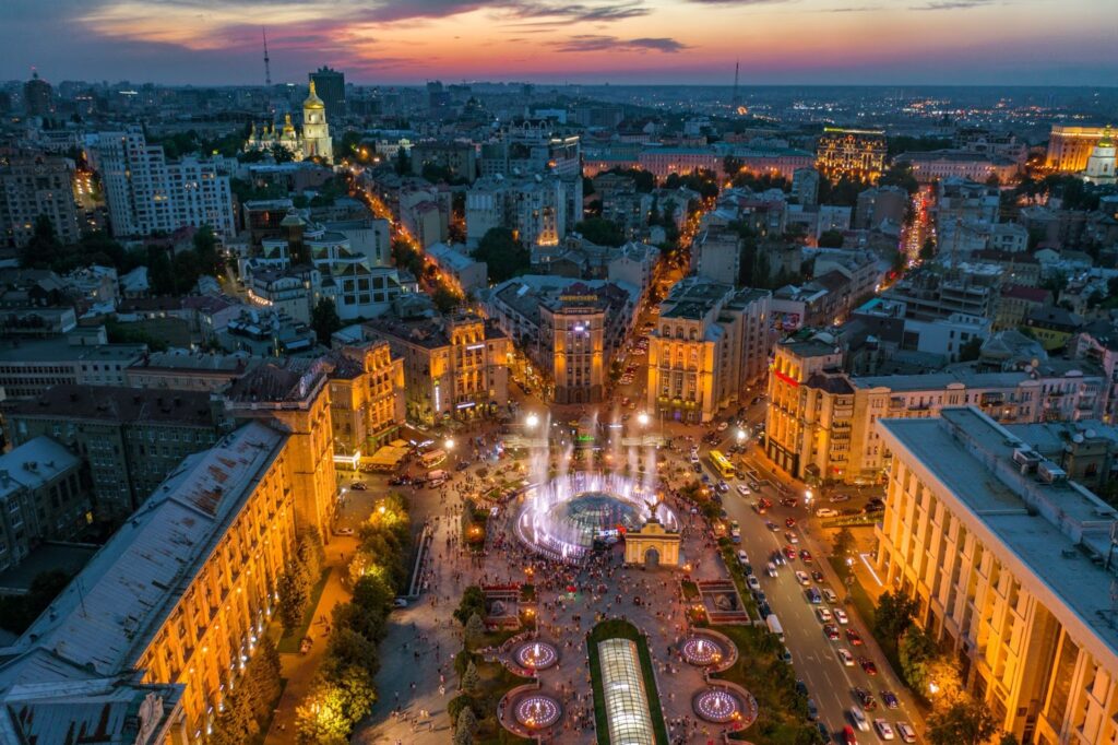 Aerial view of Kyiv's Independence Square during twilight with city lights and buildings.