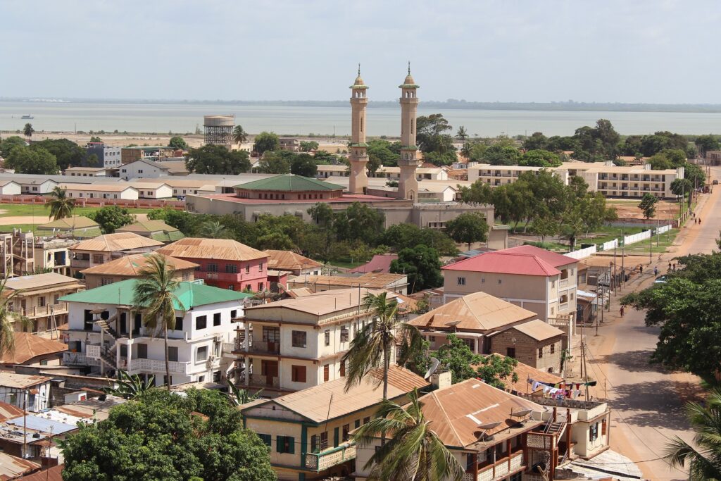 Aerial view of Banjul, the capital of Gambia, showcasing a cityscape with buildings, two prominent minarets, and a river in the background.