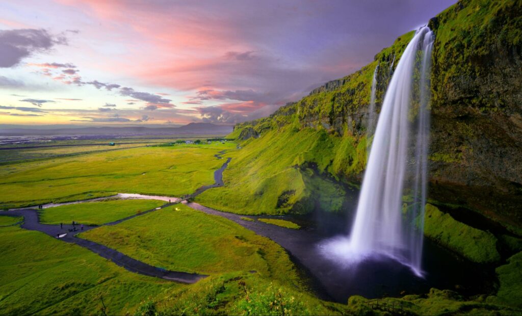 Seljalandsfoss Waterfall in Iceland with clouds at sunset in the background.