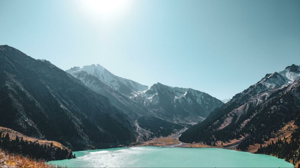 A lake surrounded by mountains, under the shining sun in the Almaty Region of Kazakhstan.