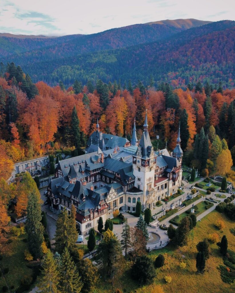 An aerial view of a castle surrounded by forest in Sinaia, Romania.