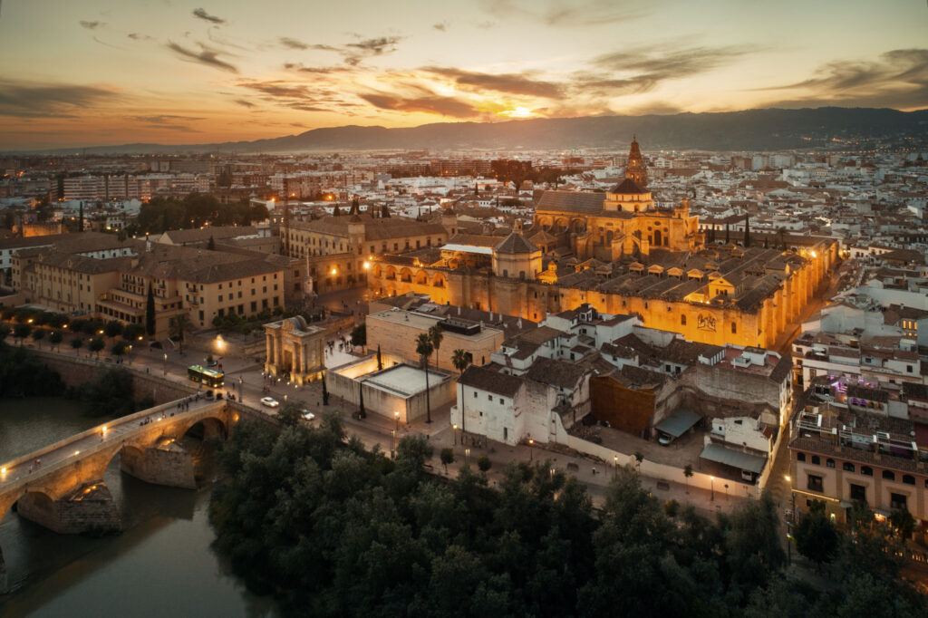 Aerial view of Córdoba, Spain at sunset with historic buildings and a river.