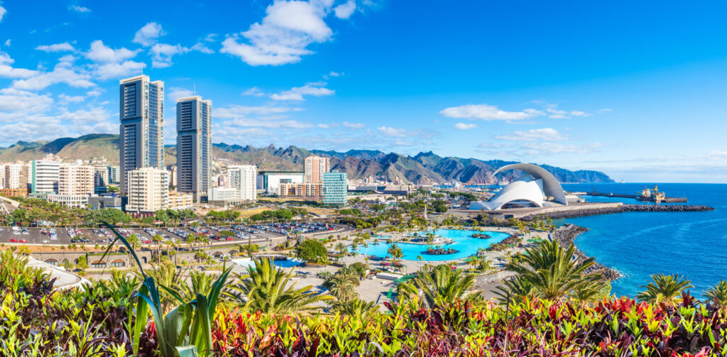 Panoramic view of Santa Cruz de Tenerife cityscape with modern buildings, blue sea, and clear sky.