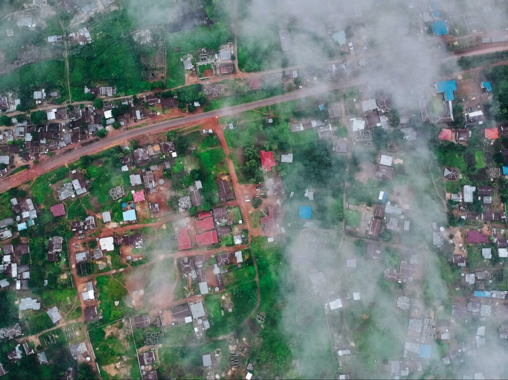 Aerial view of a cloudy and green landscape with scattered buildings, possibly in Sierra Leone.