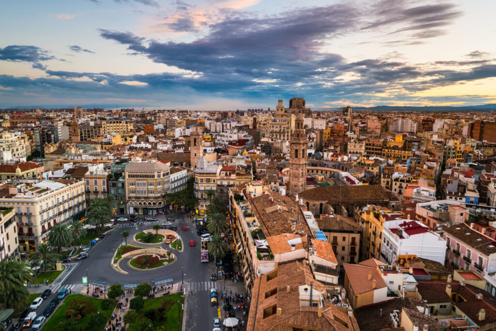 Aerial view of Valencia cityscape at dusk with buildings and streets under a cloudy sky.