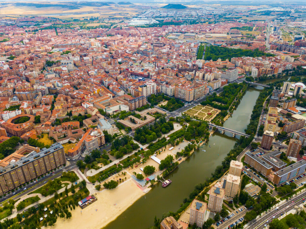 Aerial view of Valladolid cityscape with buildings, river, and greenery.