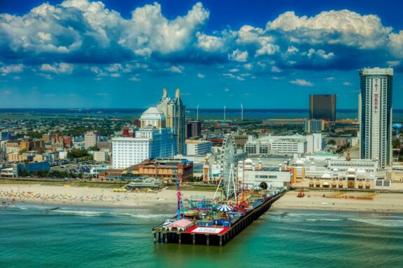 Aerial view of Atlantic City, New Jersey, showcasing the coastline, buildings, a pier, and the ocean under a partly cloudy sky.