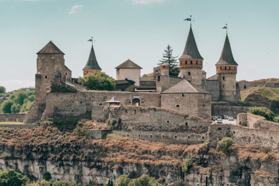 The Kamianets-Podilskyi Castle in Ukraine is a medieval fortress with multiple towers, fortified walls, and situated on a rocky outcrop.