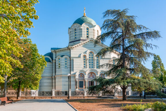 A cathedral in Sevastopol with a large dome and arched windows, surrounded by trees under a clear blue sky.