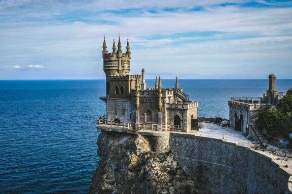 A scenic view of the Swallow's Nest Castle perched on the edge of a cliff overlooking the sea in Crimea.