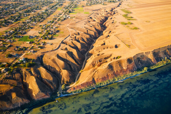 Aerial view of the Grand Canyon with the Colorado River visible, showcasing the steep-sided canyon characterized by its layered bands of red rock.