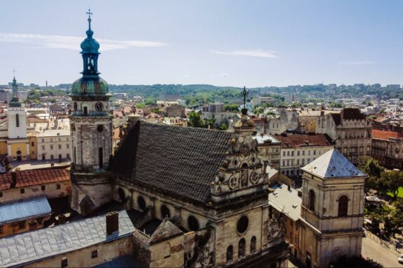 Aerial view of Lviv cityscape with historical buildings and a prominent church tower under a clear sky.