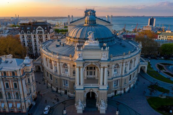 Aerial view of the Odessa Opera and Ballet Theater at dusk with surrounding buildings and streets in Odessa, Ukraine.