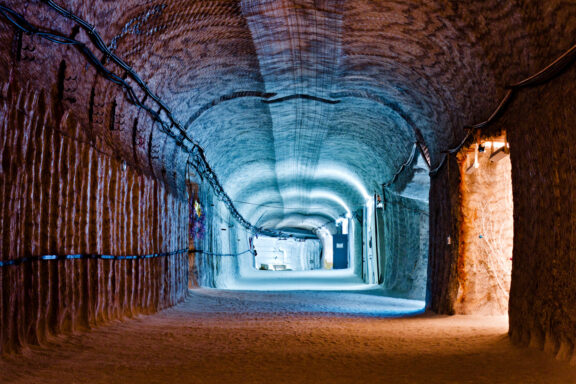 An image of the interior of the Soledar salt mine in Donetsk, featuring illuminated underground tunnels with textured walls and a sandy floor.