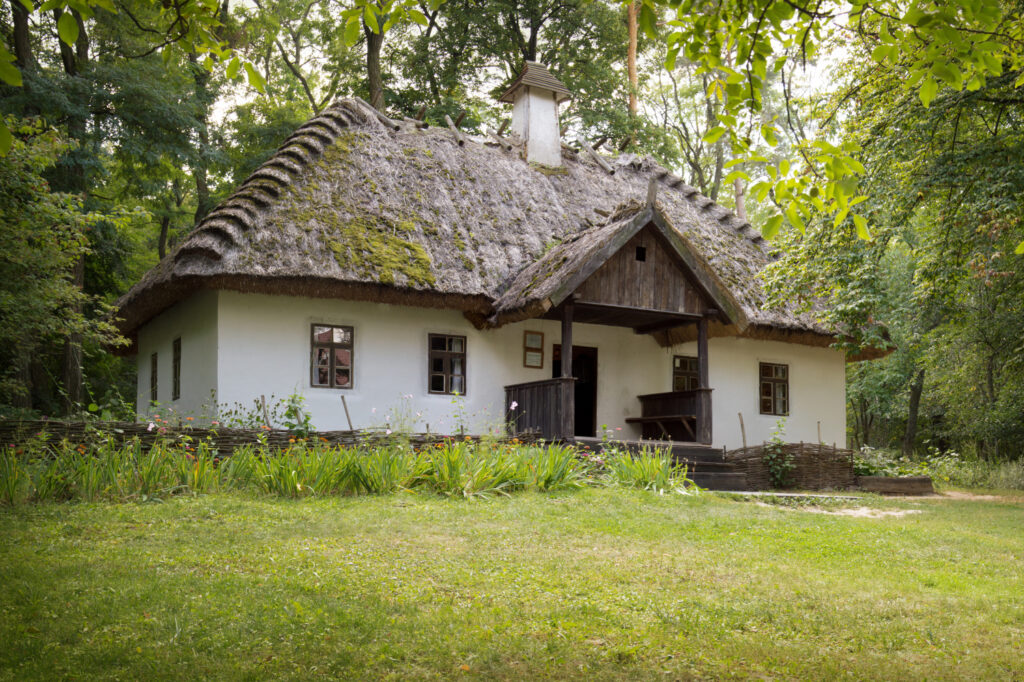 National memorial of renowned poet cobzar Taras Shevchenko in Kanev, Cherkassy region. Aged typical peasant clay white homestead 19th century. Front view and space for text on green grass lawn