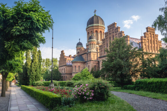 A photo shows the ornate Three Saints Orthodox Church with a dome and towers, set against greenery and a blue sky.