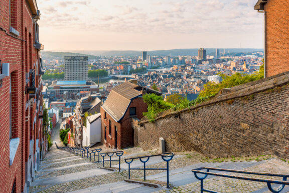 The skyline of Liège, Belgium showcases a mix of historic and modern buildings under a clear sky.