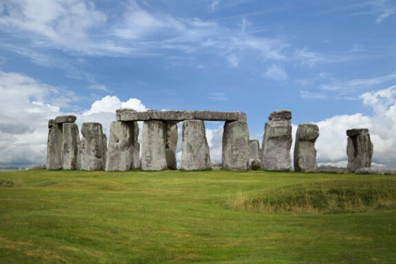 A photo of Stonehenge, the prehistoric monument, featuring a circle of standing stones set against a partly cloudy sky.