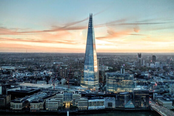 Aerial view of The Shard skyscraper in London during sunset with cityscape in the background.