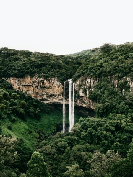 A waterfall cascading down a steep cliff surrounded by lush green vegetation in Caracol Falls, Rio Grande do Sul, Brazil.