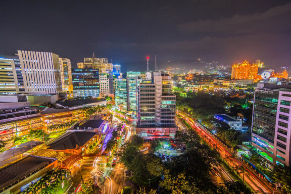 A nighttime cityscape of Cebu City with illuminated buildings and streets, showcasing a bustling urban area.