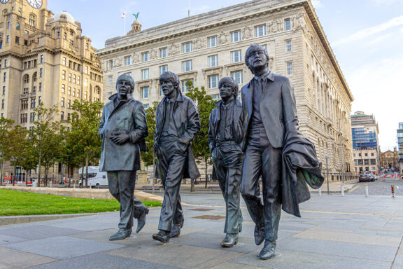 A statue of four figures walking side by side in Liverpool.