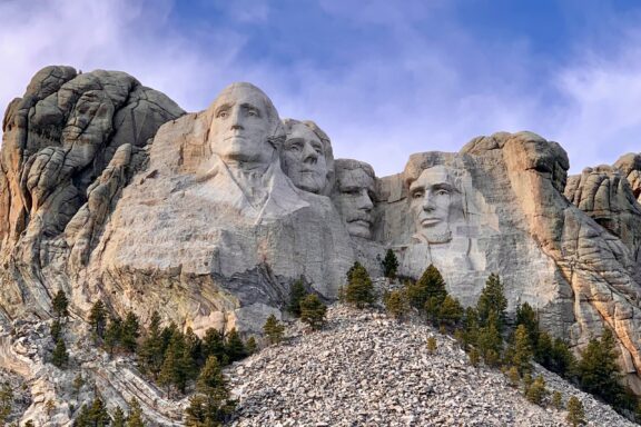 An image of Mount Rushmore National Memorial in South Dakota, showing the carved faces of four former U.S. presidents on a rocky mountainside.