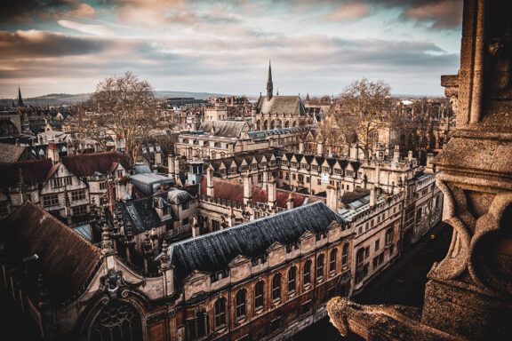 Aerial view of Oxford cityscape at dusk with historic buildings and a cloudy sky.